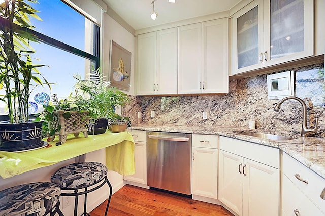 kitchen with wood-type flooring, backsplash, stainless steel dishwasher, and sink