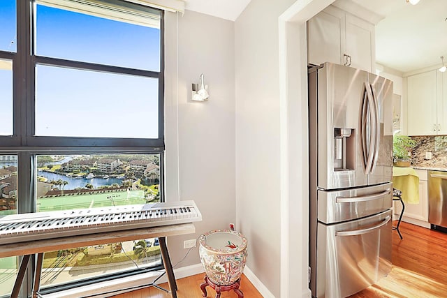 kitchen with white cabinets, stainless steel appliances, a healthy amount of sunlight, and a water view