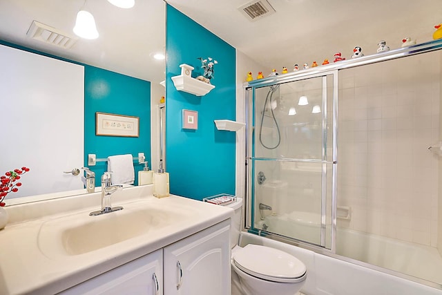 full bathroom featuring combined bath / shower with glass door, vanity, and toilet