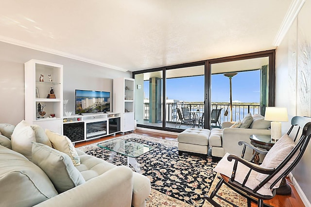 living room featuring built in shelves, hardwood / wood-style flooring, expansive windows, and crown molding