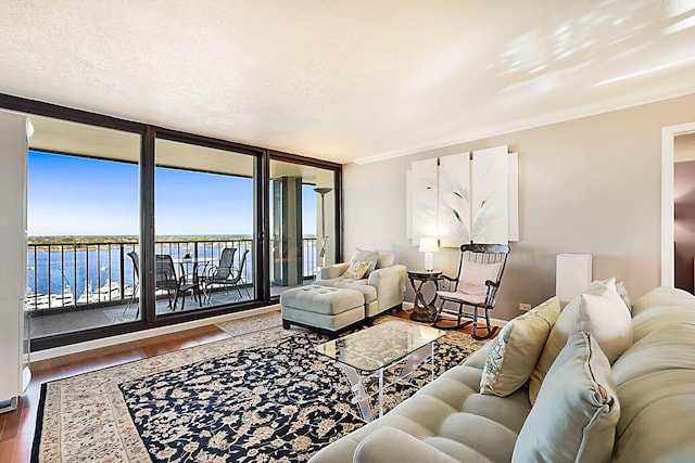 living room with floor to ceiling windows, a water view, ornamental molding, and hardwood / wood-style flooring