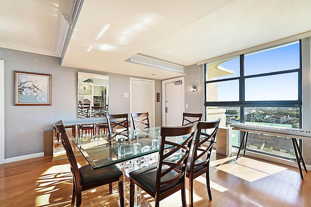 dining area featuring wood-type flooring, crown molding, and a wealth of natural light