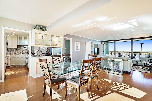 dining area featuring expansive windows, ornamental molding, and hardwood / wood-style flooring