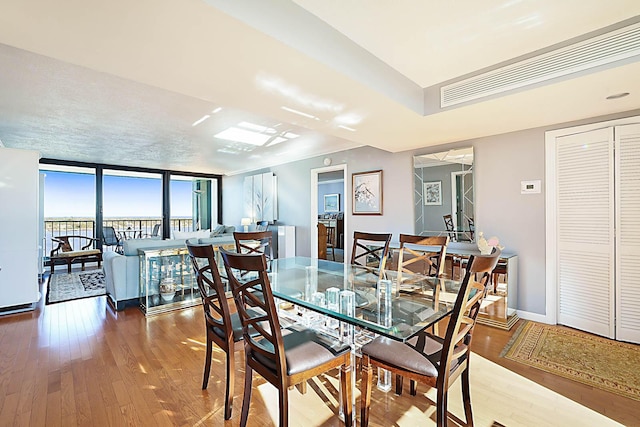 dining area with a wall of windows and hardwood / wood-style flooring