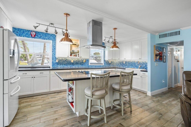 kitchen featuring white cabinetry, hanging light fixtures, white refrigerator with ice dispenser, crown molding, and island range hood