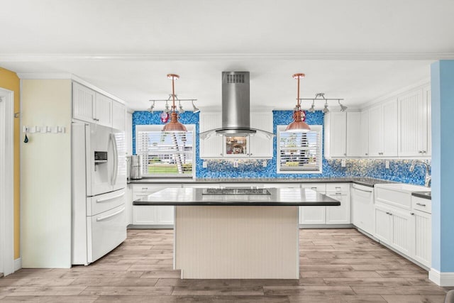 kitchen featuring white refrigerator with ice dispenser, light wood finished floors, dark countertops, a sink, and island range hood