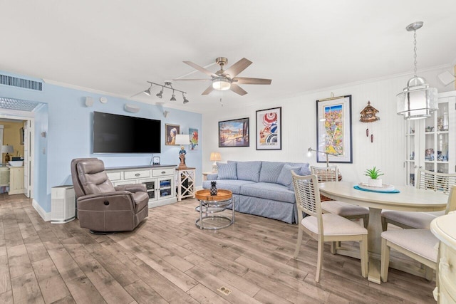 living room with ceiling fan, visible vents, ornamental molding, and wood finished floors