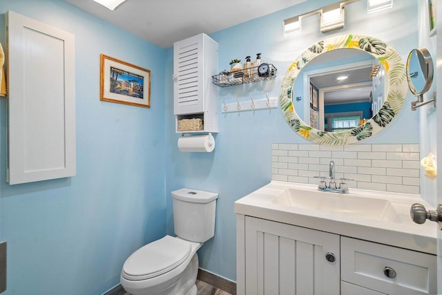 bathroom with tasteful backsplash, hardwood / wood-style floors, vanity, and toilet