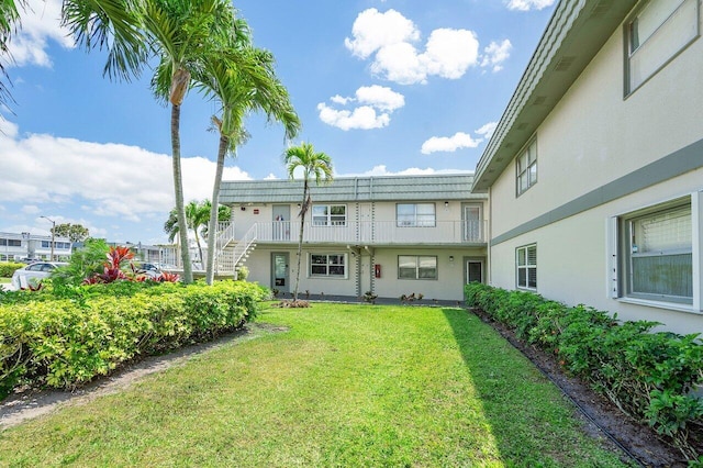 back of property featuring a lawn and stucco siding