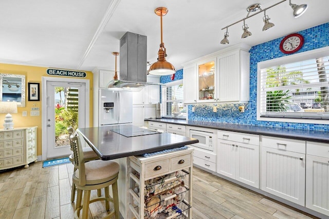 kitchen with a wealth of natural light, stainless steel fridge, white microwave, and hanging light fixtures