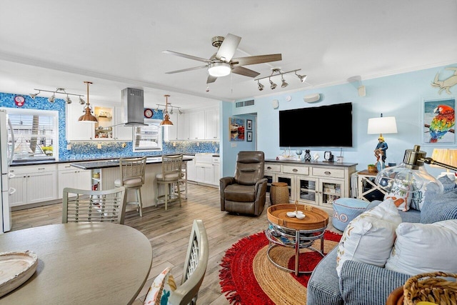 living room featuring light hardwood / wood-style floors, ceiling fan, and ornamental molding