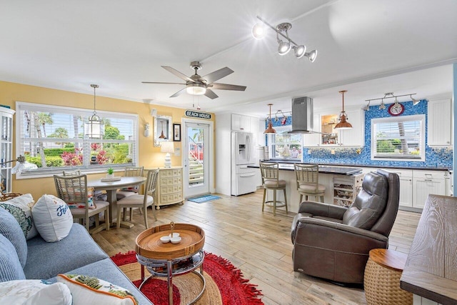 living room featuring a wealth of natural light, light hardwood / wood-style flooring, ceiling fan, and crown molding