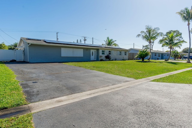 ranch-style home featuring solar panels and a front lawn