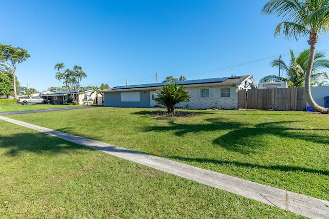 view of front of home featuring a front lawn and solar panels