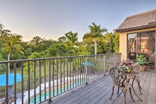 deck at dusk featuring a fenced in pool