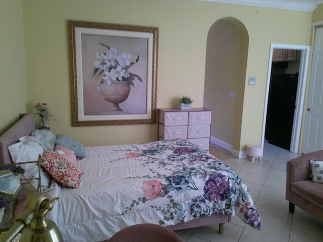 bedroom with light tile patterned floors, black fridge, and ornamental molding