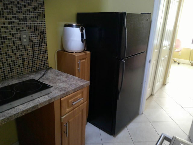 kitchen with white electric cooktop, black refrigerator, and light tile patterned floors