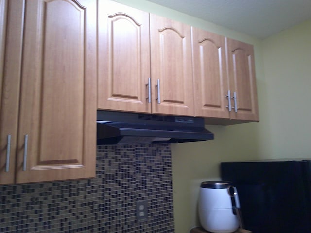 interior space featuring light brown cabinets and tasteful backsplash