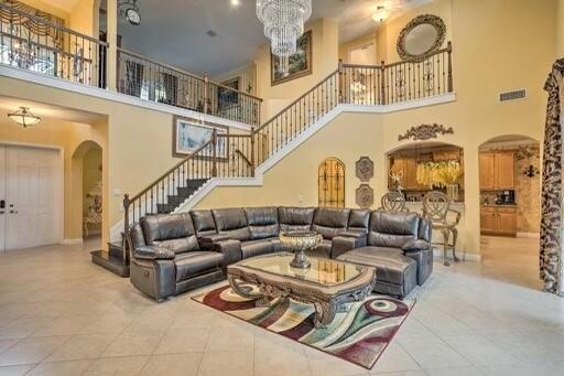 tiled living room featuring a high ceiling and an inviting chandelier