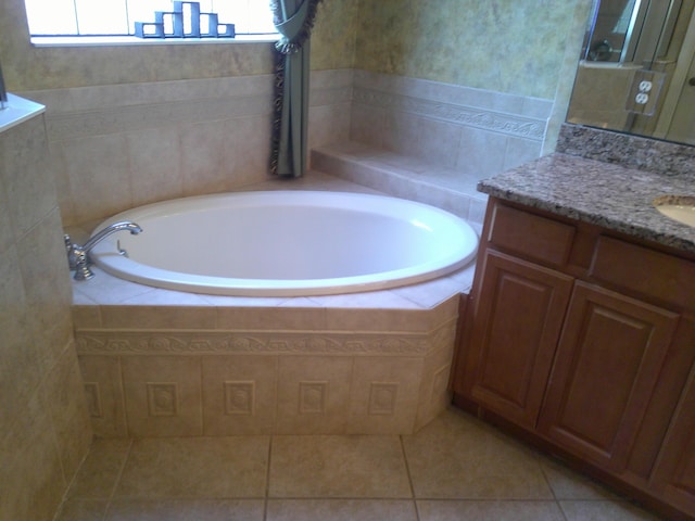 bathroom featuring tile patterned flooring, vanity, and tiled tub