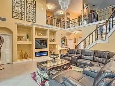 living room with a towering ceiling, built in features, and a notable chandelier