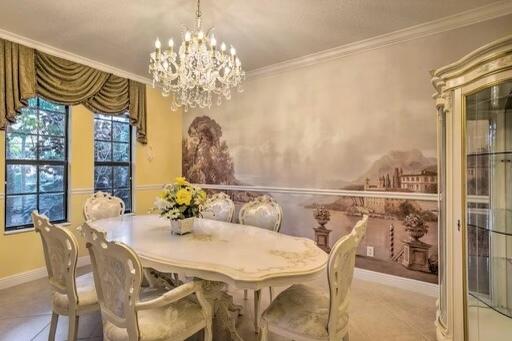 dining space with a notable chandelier, light tile patterned floors, and crown molding