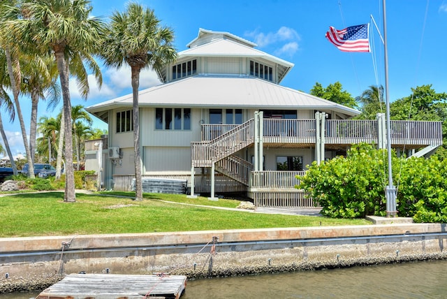 back of house featuring a water view and a lawn