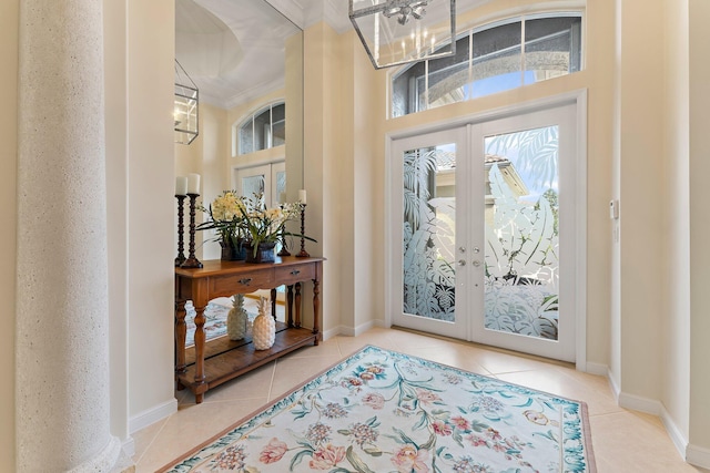 tiled entrance foyer featuring a notable chandelier, crown molding, and french doors