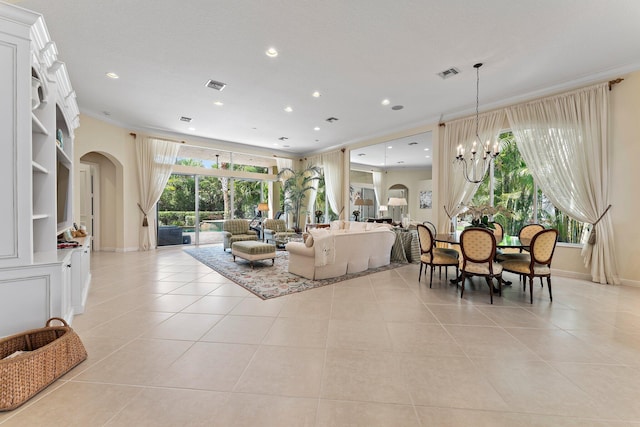 living room with light tile patterned floors, ornamental molding, and an inviting chandelier