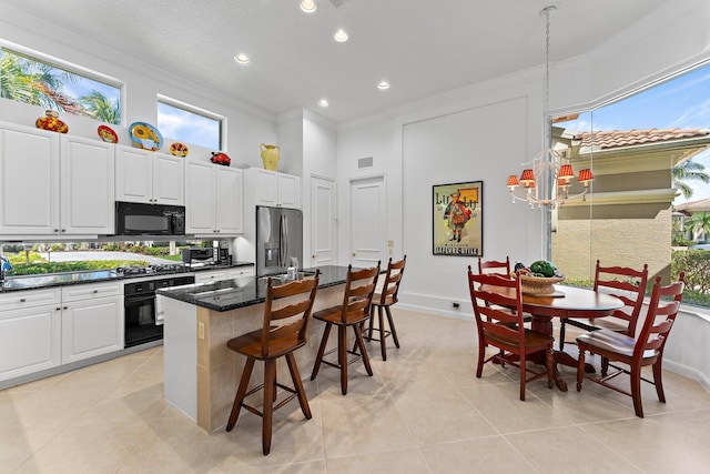 kitchen featuring a kitchen bar, a center island with sink, black appliances, and ornamental molding