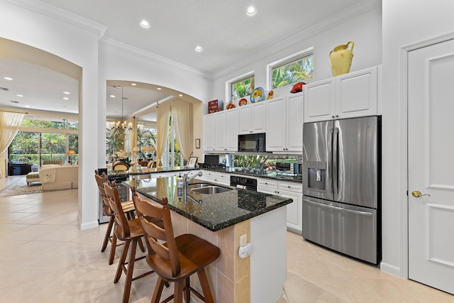 kitchen with dark stone counters, black appliances, a kitchen breakfast bar, sink, and white cabinetry