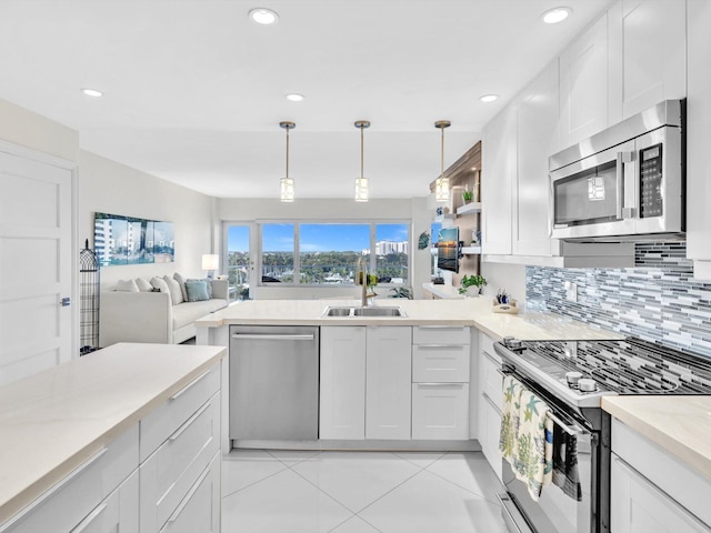 kitchen featuring appliances with stainless steel finishes, decorative light fixtures, white cabinetry, and sink