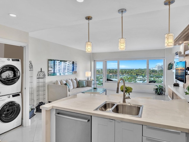 kitchen featuring white cabinetry, dishwasher, sink, stacked washer and dryer, and pendant lighting