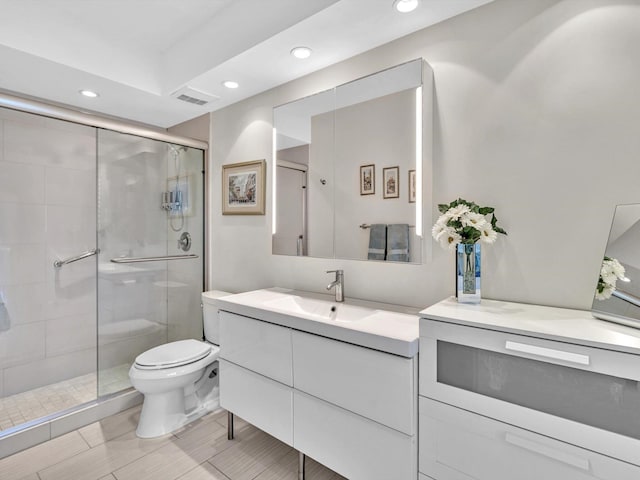 bathroom with vanity, toilet, and a shower with door