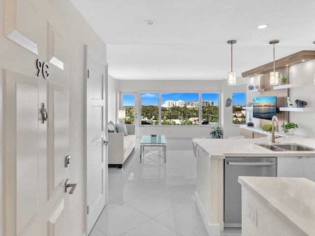 kitchen featuring stainless steel dishwasher, sink, pendant lighting, light tile patterned floors, and white cabinets