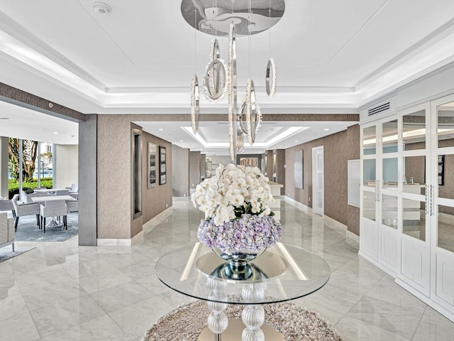 interior space featuring french doors, a raised ceiling, and a notable chandelier