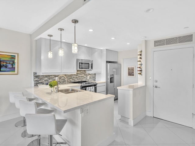 kitchen with a breakfast bar, white cabinets, decorative light fixtures, kitchen peninsula, and stainless steel appliances