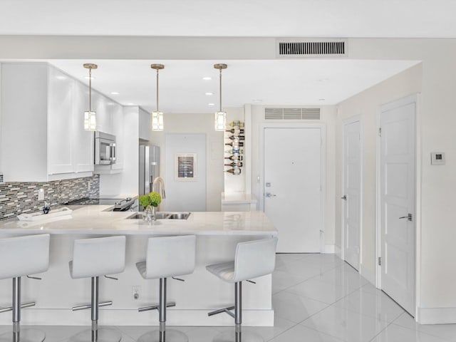 kitchen with kitchen peninsula, pendant lighting, stainless steel appliances, and a kitchen breakfast bar