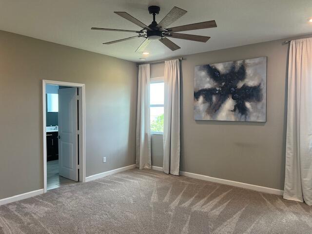 unfurnished bedroom featuring carpet, ceiling fan, and connected bathroom