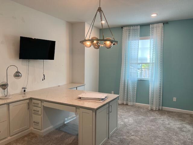 kitchen featuring pendant lighting, kitchen peninsula, and light carpet