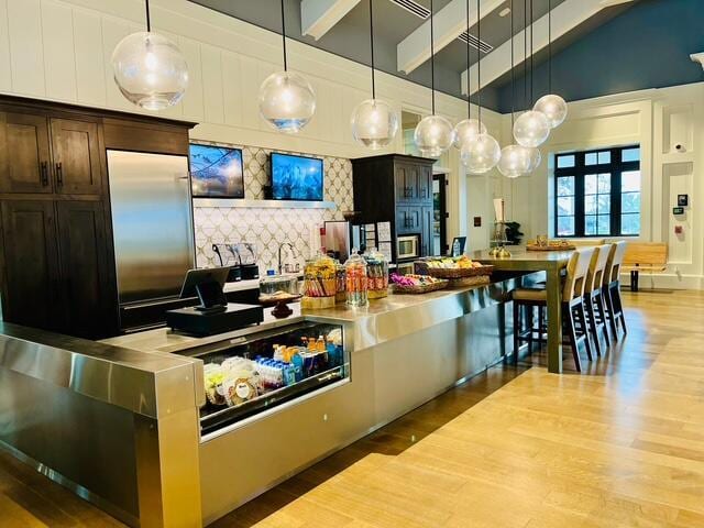 kitchen with dark brown cabinets, decorative light fixtures, high vaulted ceiling, beamed ceiling, and hardwood / wood-style floors