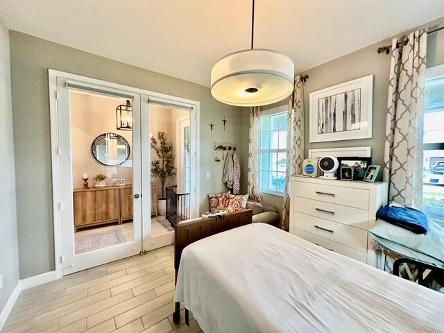 bedroom featuring french doors, light wood-type flooring, and multiple windows