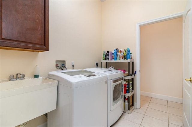 laundry room featuring washing machine and dryer, sink, light tile patterned flooring, and cabinets