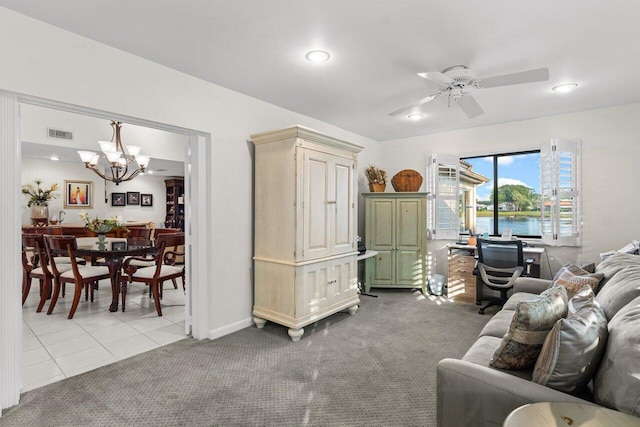 living room with light carpet, ceiling fan with notable chandelier, and a water view