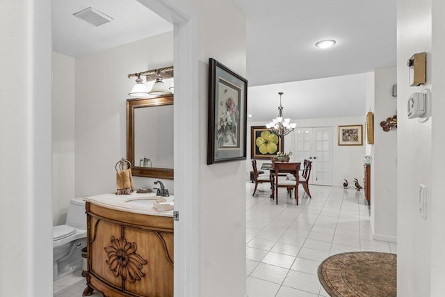 corridor featuring light tile patterned floors, sink, and a chandelier