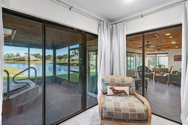 doorway featuring carpet floors, ceiling fan, a water view, and a textured ceiling