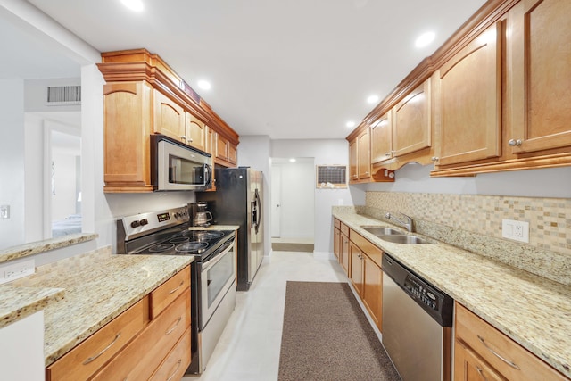 kitchen featuring decorative backsplash, appliances with stainless steel finishes, light stone counters, and sink