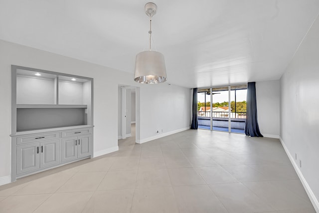 unfurnished living room with built in shelves and light tile patterned floors