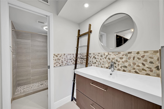 bathroom featuring a tile shower, vanity, and tile walls