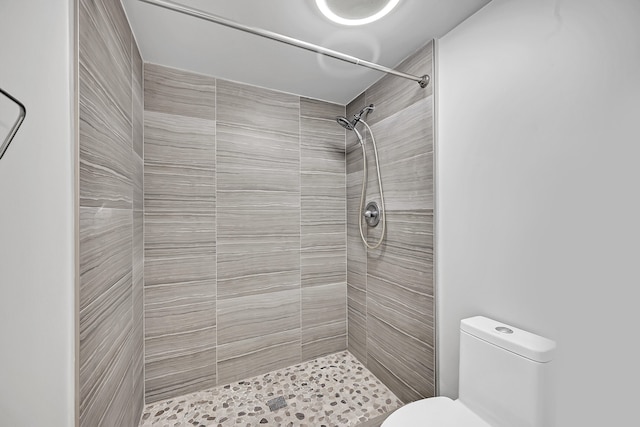 bathroom featuring a tile shower and toilet